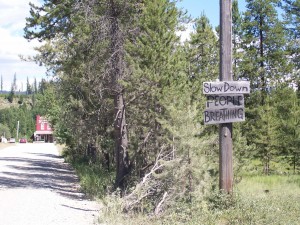 sign by a dusty gravel road reads: "Slow down - people breathing"_Polebridge, MT