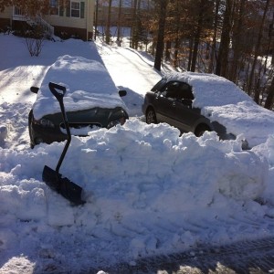 snow piled in front of cars ready to shovel